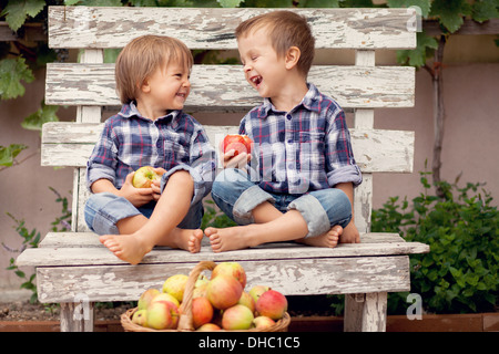 Due ragazzi con un cesto di mele, seduta su una panchina Foto Stock