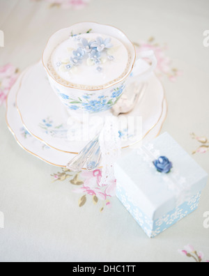 Una cina floreali cup, piattino e piastra, con iced cupcake torta e box Foto Stock