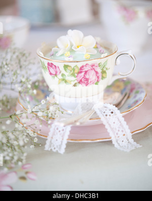 Una cina floreali cup, piattino e piastra, con iced cupcake Foto Stock