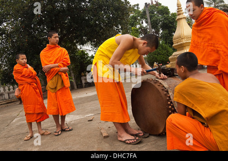 Ritratto orizzontale di giovani monaci buddisti rammendo un tamburo cerimoniale presso il loro tempio a Luang Prabang. Foto Stock