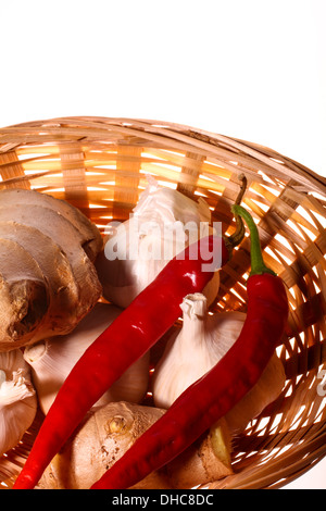 Raccolta di aglio, zenzero e peperoncino in un cesto su sfondo bianco Foto Stock