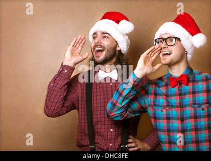 Due ragazzi in hipster vestiti di Babbo Natale in un grido di Natale Foto Stock