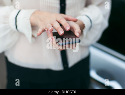 Giovane bella donna scrive un SMS al telefono cellulare. Foto Stock