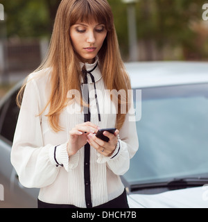 Giovane bella donna scrive un SMS al telefono cellulare. Foto Stock