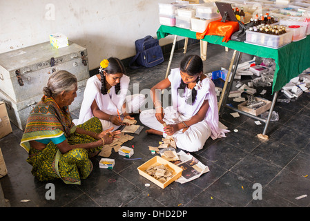 Donna indiana e ragazze mettendo la vitamina B compresse in pacchetti a Sri Sathya Sai Baba outreach mobile farmacia ospedaliera. India Foto Stock