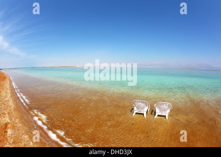 Due spiagge di sabbia bianca di sedie si fermò in acqua Foto Stock