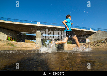 Germania Baden-Wuerttemberg, Winterbach, atletica giovane uomo che corre attraverso il fiume rem Foto Stock