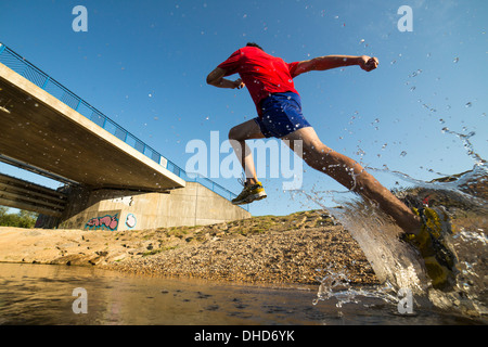 Germania Baden-Wuerttemberg, Winterbach, atletica giovane uomo che corre attraverso il fiume rem Foto Stock