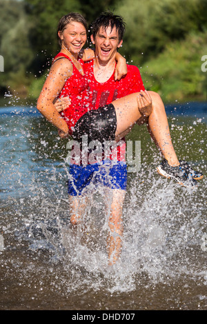 Germania Baden-Wuerttemberg, Winterbach, atletica giovane carring giovane donna mentre si esegue attraverso rem river Foto Stock