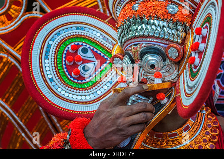 Un artista Theyyam in maschera a pieno facciale, colorato costume, e make-up durante le prestazioni, Kannur, Kerala, India. Foto Stock