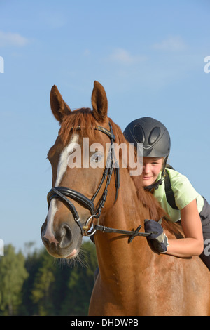 Tredici-anno-vecchia ragazza che indossa un casco e una protezione posteriore sul retro di un Irish Sport Pony cavallo Foto Stock