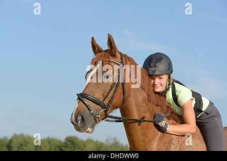 Tredici-anno-vecchia ragazza che indossa un casco e una protezione posteriore sul retro di un Irish Sport Pony cavallo Foto Stock