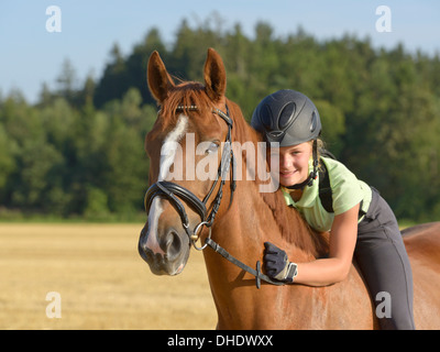 Tredici-anno-vecchia ragazza che indossa un casco e una protezione posteriore sul retro di un Irish Sport Pony cavallo Foto Stock