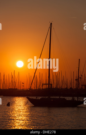 Il Rising Sun trasforma il cielo arancione su barche a vela e altre imbarcazioni da diporto ormeggiata nel porto di Annapolis, Maryland. Foto Stock
