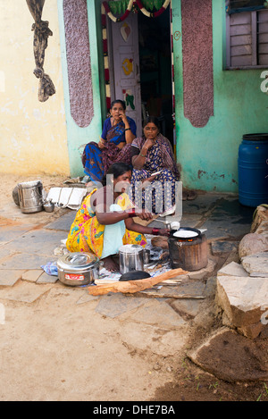 Donna indiana che dosa di cottura per le persone al di fuori di un villaggio rurale casa. Andhra Pradesh, India Foto Stock