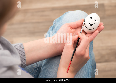 La ragazza richiama con un pennello su un uovo bianco. Uovo ride. Foto Stock