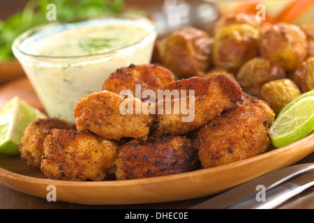 Panato calamari fritti pezzi con piccole patate al forno e tzatziki Foto Stock