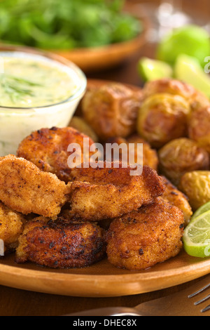 Panato calamari fritti pezzi con piccole patate al forno e tzatziki Foto Stock