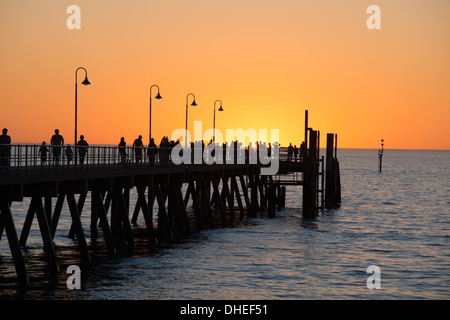 Persone che si godono una passeggiata al tramonto lungo il molo di Glenelg Jetty Australia in estate Foto Stock