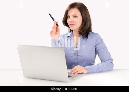 Imprenditrice è seduta davanti a un laptop moderno e indicando con la punta di una penna a sfera, la concezione di business Foto Stock