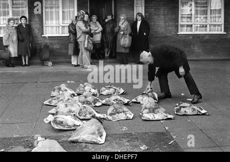 Corone funebri, donne locali si riuniscono per guardare il direttore funebre disporre le corone sul marciapiede di fronte alle persone malate a casa. Hoxton, East End Londra Regno Unito 1978. 1970 UK HOMER SYKES Foto Stock