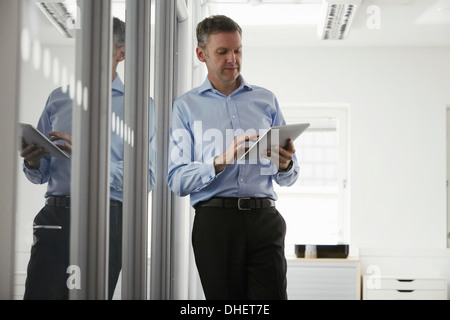 Uomo con tavoletta digitale in ufficio Foto Stock