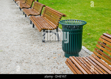 Green spazzatura e panca in legno nel parco della città Foto Stock