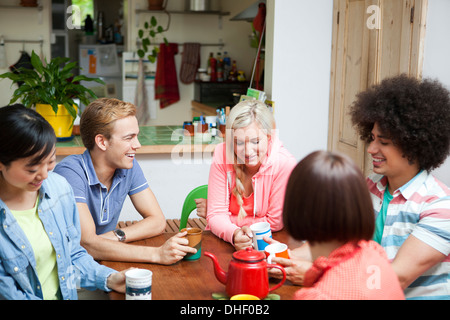 Un gruppo di giovani amici in chat intorno al tavolo della cucina Foto Stock