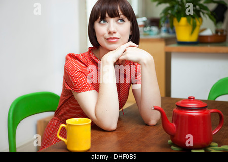Ritratto di giovane donna seduta al tavolo della cucina Foto Stock