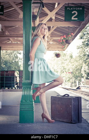 Giovane bella bionda ragazze in attesa in un vintage stazione ferroviaria Foto Stock