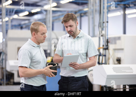 Due lavoratori guardando digitale compressa nel magazzino di ingegneria Foto Stock