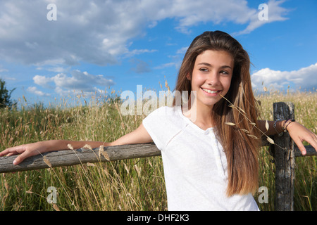 Ragazza adolescente appoggiata sulla staccionata in legno, Toscana, Italia Foto Stock