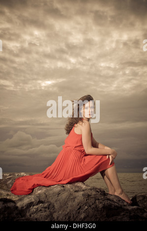 Bruna modello sulla spiaggia rocciosa durante una tempesta Foto Stock