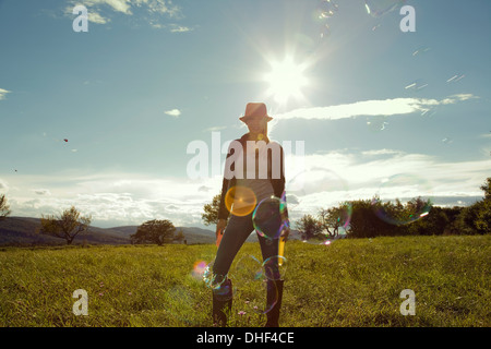 Giovane donna in campo con bolle soffiate Foto Stock