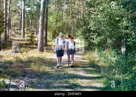 I genitori di dare le figlie piggy back attraverso la foresta Foto Stock