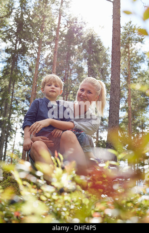 Ragazzo seduto sulla madre di giro in foresta Foto Stock