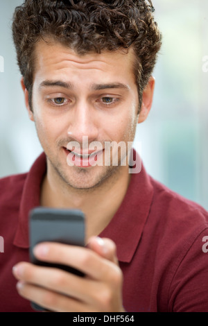 Giovane uomo che guarda un messaggio di testo sul telefono cellulare Foto Stock