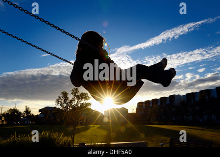 Giovane ragazza su swing al tramonto Foto Stock