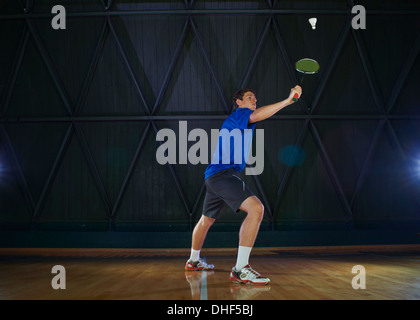 Giovane uomo giocando badminton su corte Foto Stock