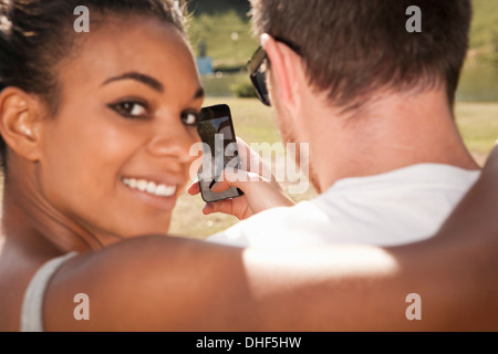 Coppia giovane di prendere una foto di loro stessi con telefono, donna guardando sopra la spalla