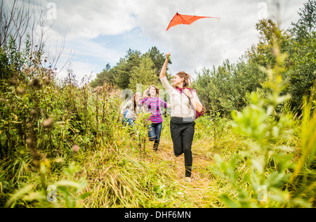 Quattro giovani donne in esecuzione attraverso la macchia con kite Foto Stock