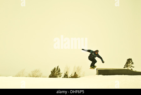 Giovane maschio snow boarder metà aria sulla montagna Foto Stock