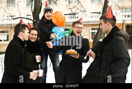 Un gruppo di giovani amici su una strada di città con torta di compleanno Foto Stock
