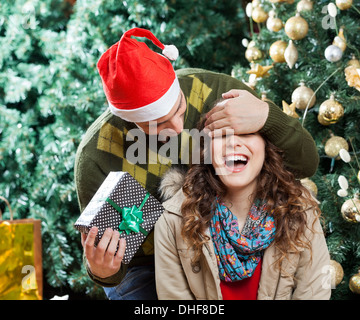 Uomo Donna sorprendente con il regalo di Natale presso lo store Foto Stock