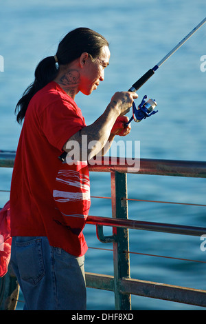 Tatuato uomo pesca dal molo di Redondo, California. Foto Stock