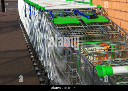 Carrello per lo shopping, inventato, 1937 Oklahoma, supermercato, Carrello per lo shopping, ASDA, immagazzinato, allineato-su, raccolto, guidato, linee, serpente, snaked, di fronte, parcheggio. Foto Stock