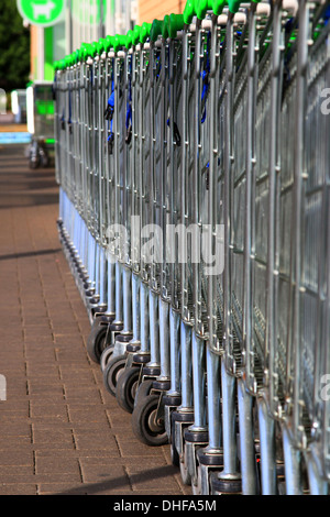 Carrello per lo shopping, inventato, 1937 Oklahoma, supermercato, Carrello per lo shopping, ASDA, immagazzinato, allineato-su, raccolto, guidato, linee, serpente, snaked, di fronte, parcheggio. Foto Stock