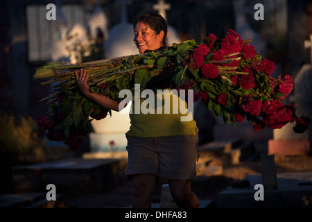 Una donna porta calendula fiori durante il giorno dei morti celebrazioni nel cimitero di Santa Ana Zegache, Oaxaca, Messico Foto Stock