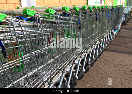 Carrello per lo shopping, inventato, 1937 Oklahoma, supermercato, Carrello per lo shopping, ASDA, immagazzinato, allineato-su, raccolto, guidato, linee, serpente, snaked, di fronte, parcheggio. Foto Stock