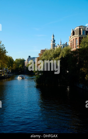 Un tour in barca scivola attraverso un canale d'acqua ad Amsterdam nei Paesi Bassi Foto Stock